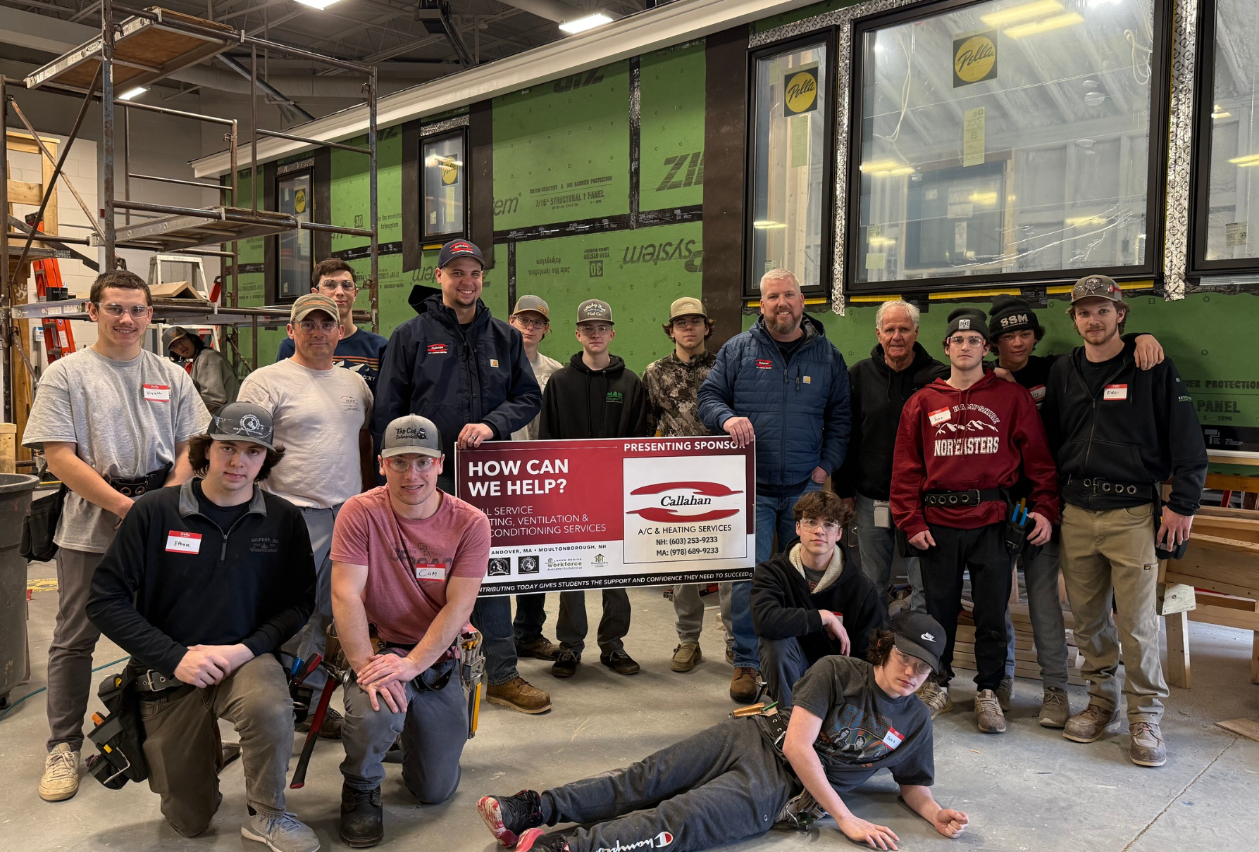 Students and instructors at the Huot Technical Center tiny house build with Callahan HVAC presenting sponsor sign